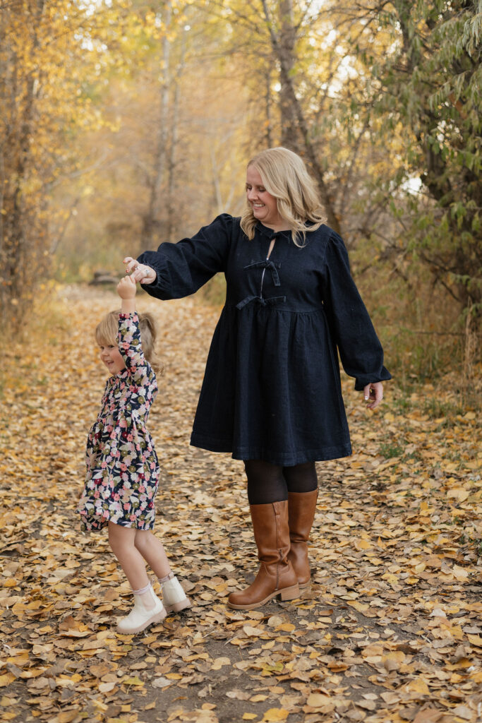 Mom and daughter playfully looking towards each other surrounded by fall colored leaves. Photo taken by Bailee Freeman Photography in Rexburg Idaho Southeast Idaho